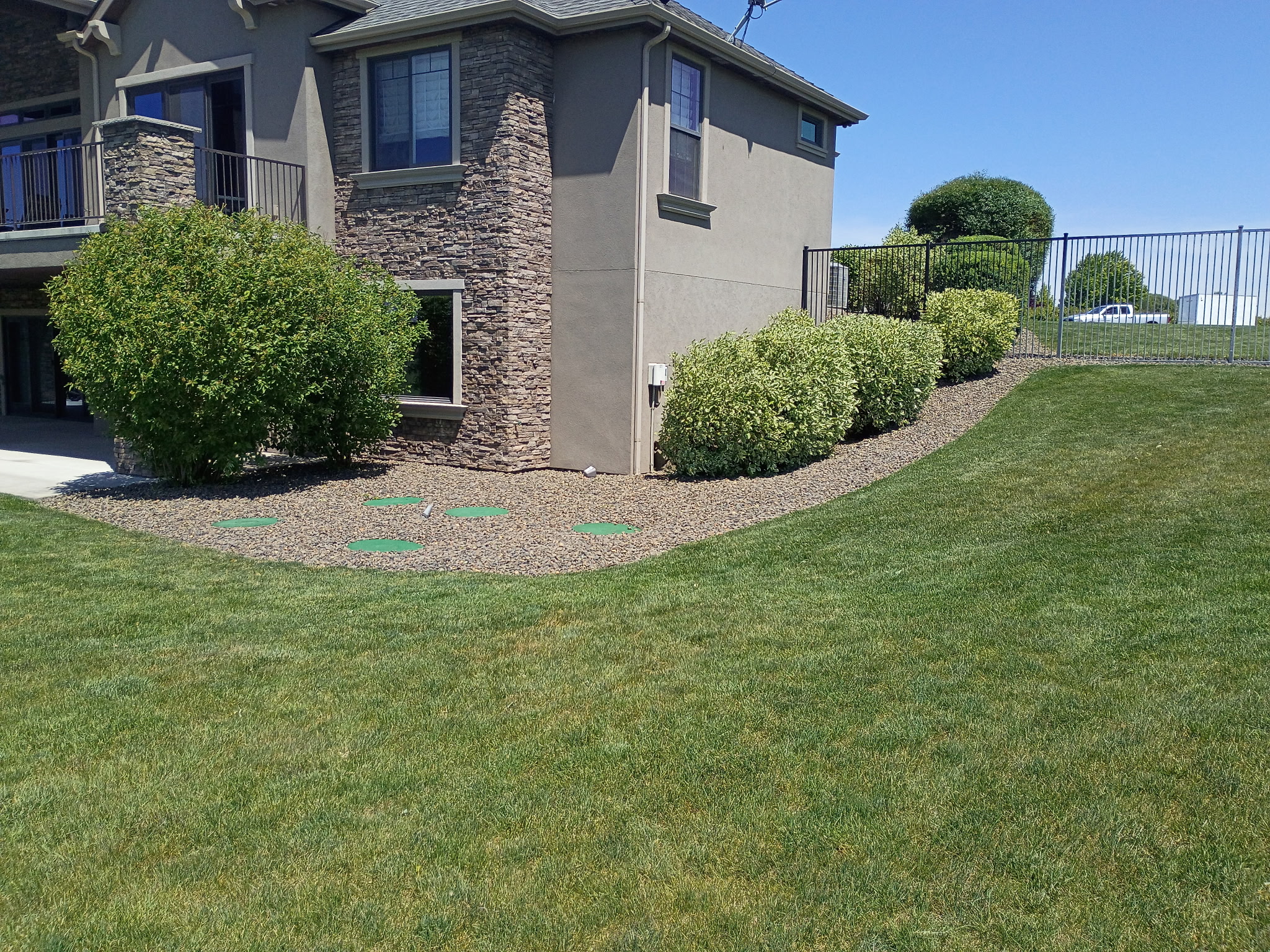 Rock landscape bed with trimmed shrubs along a house